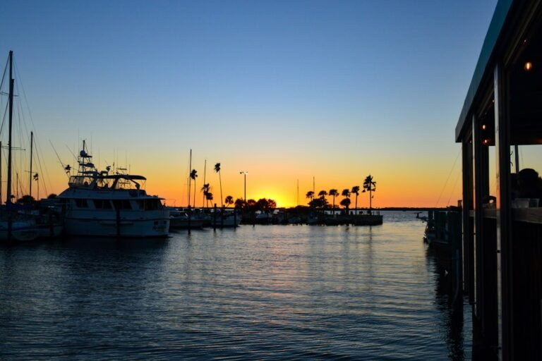 Golden Florida sunset over a calm waterfront with boats and palm trees